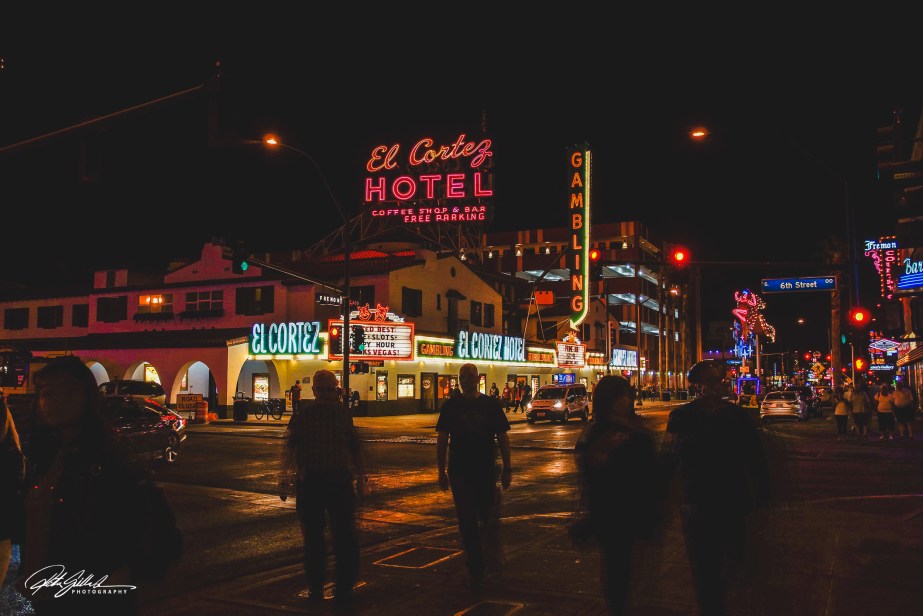 Nighttime view of El Cortez Hotel in Las Vegas, featuring bright neon signs and pedestrians walking along the street.