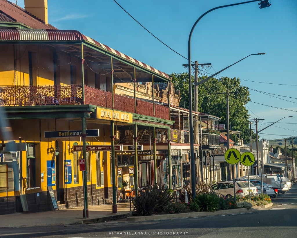 Street view of the Royal Hotel with vintage architecture and colorful facades, highlighting local shops and street signs.