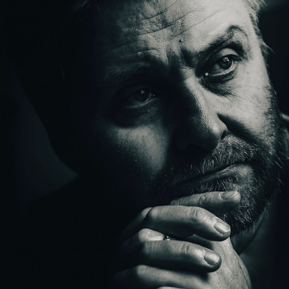 A black and white portrait of a contemplative man, displaying deep emotion and introspection.